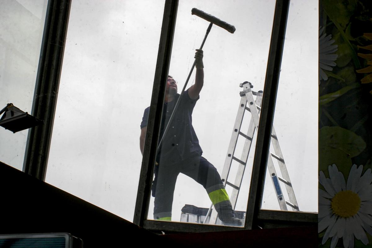 Un trabajador limpiando una cristalera